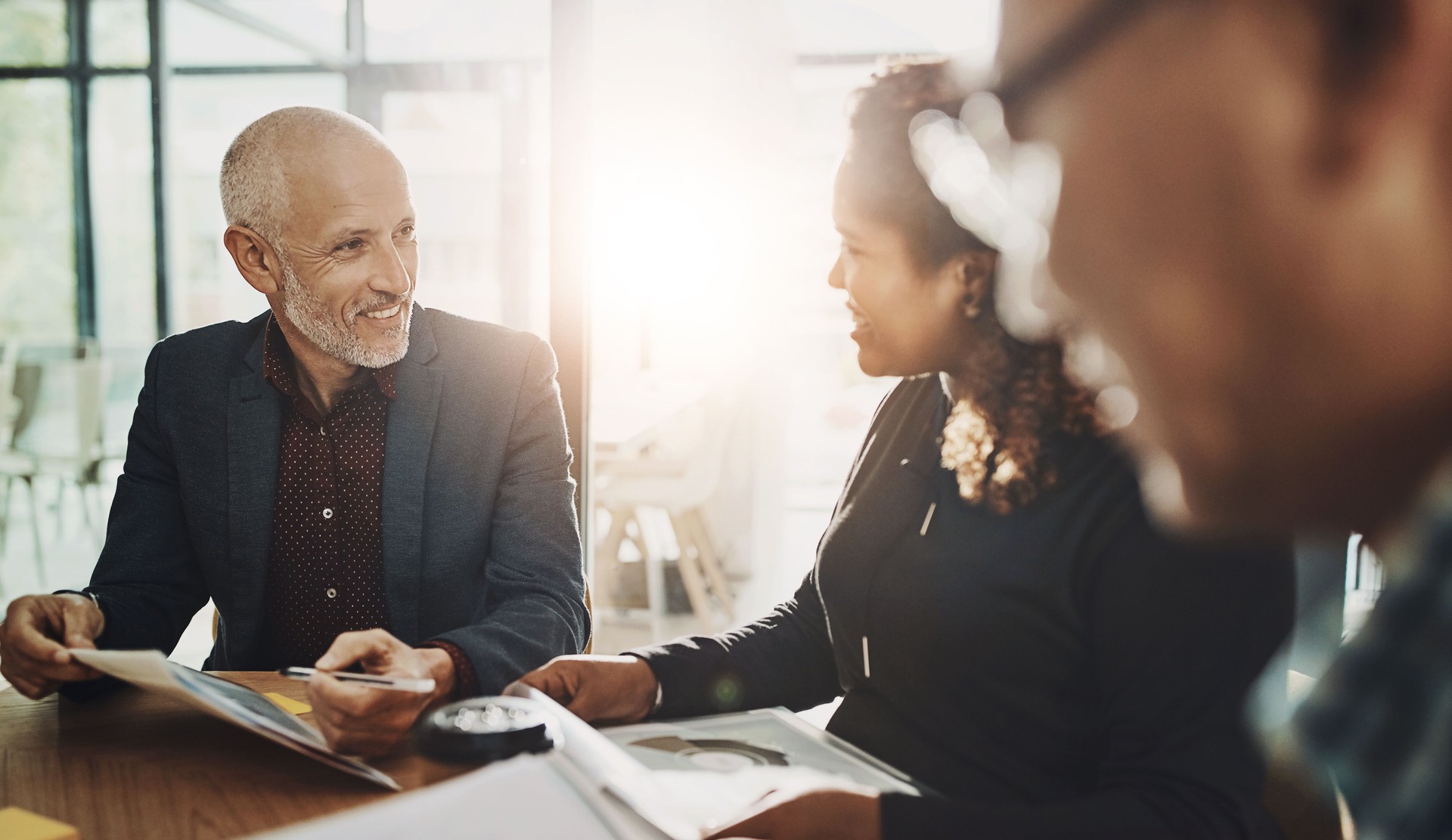 Financial advisor, accounting or mature businessman in meeting for budget strategy or paperwork. Smile, research or investment banker talking to manager finance, advice or growth report documents